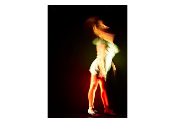 A blurred photo of a dancer, taken side on and in low light.