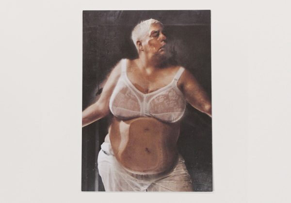 This postcard displays a female figure pressing themselves against a glass pane, with the effect being as if they are pressing themselves against the postcard themselves.